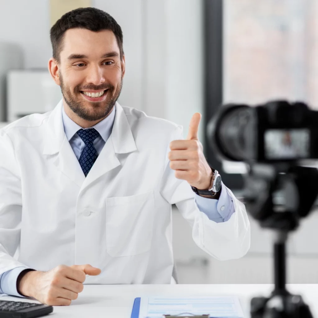 Doctor giving a thumbs up at a video camera